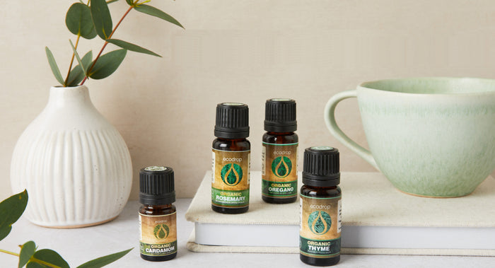 Organic Essential oils bottles on a surface with a vase and books in the background