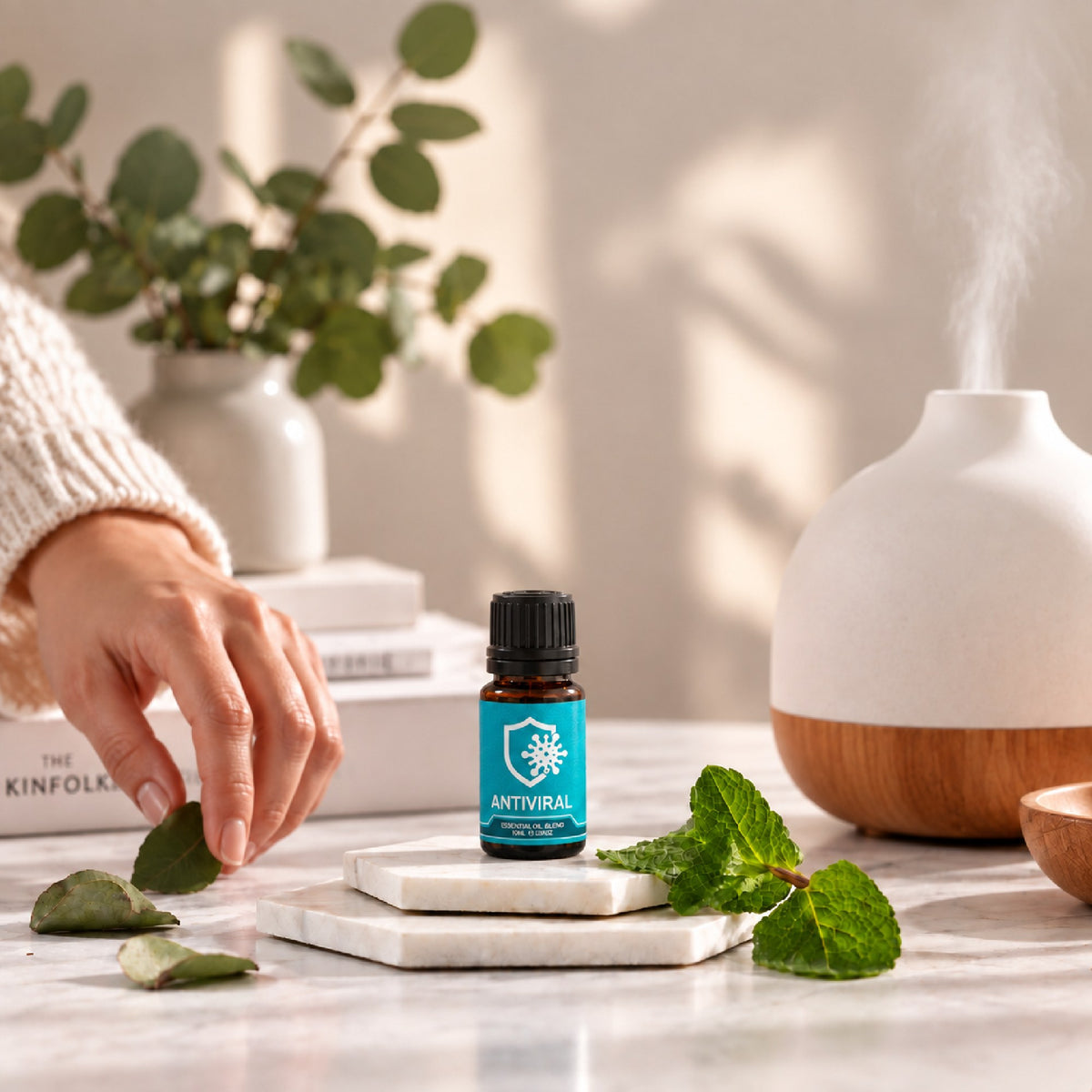 Antiviral essential oil blend on marble beside a diffuser and fresh mint