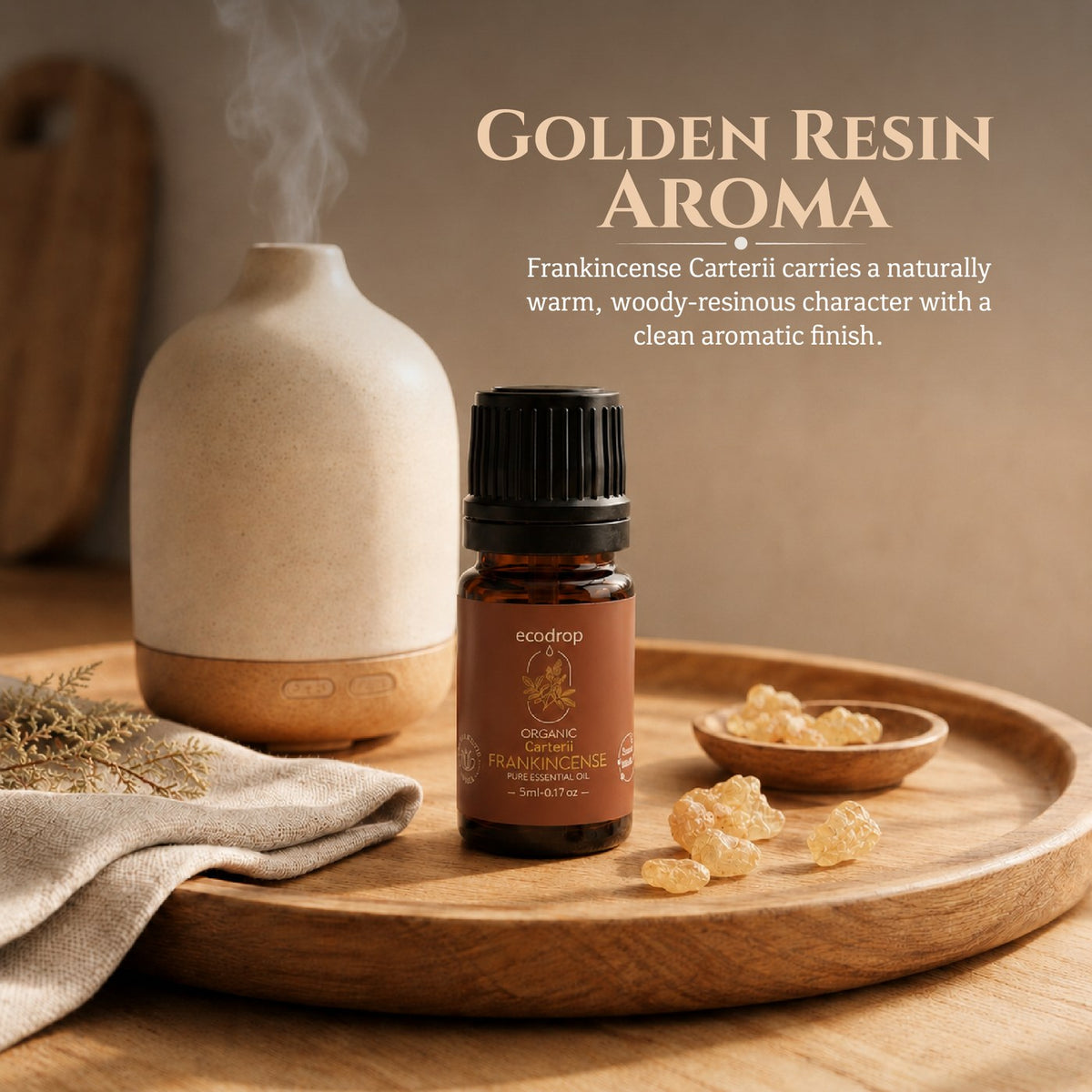 Frankincense Carterii essential oil beside a diffuser and golden resin tears