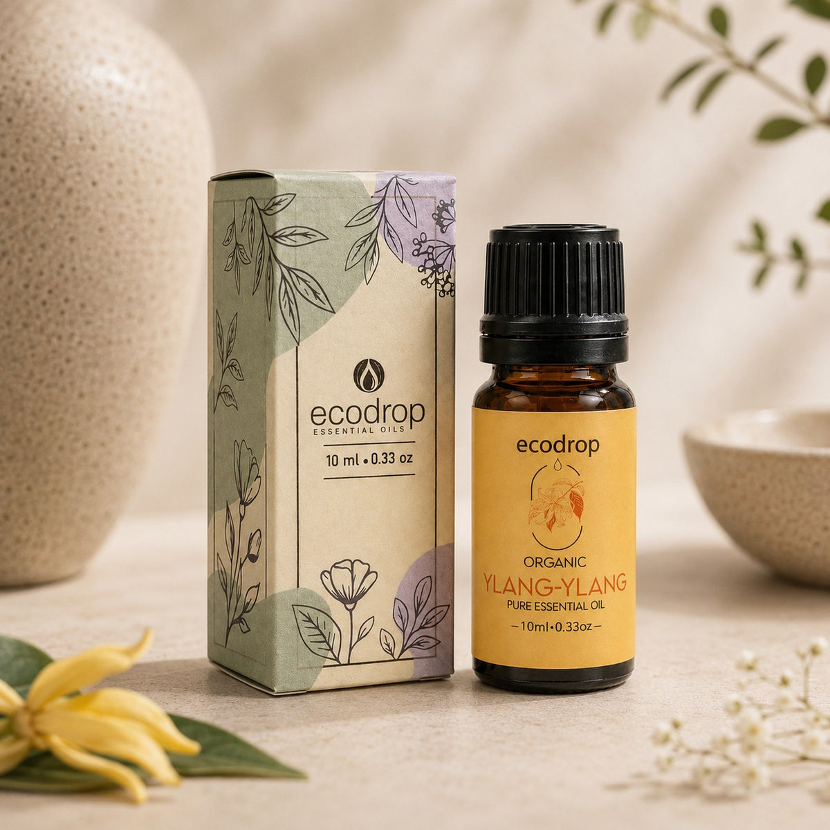 Organic Ylang Ylang Essential Oil 10ml bottle beside its botanical ecodrop box with fresh ylang ylang flowers