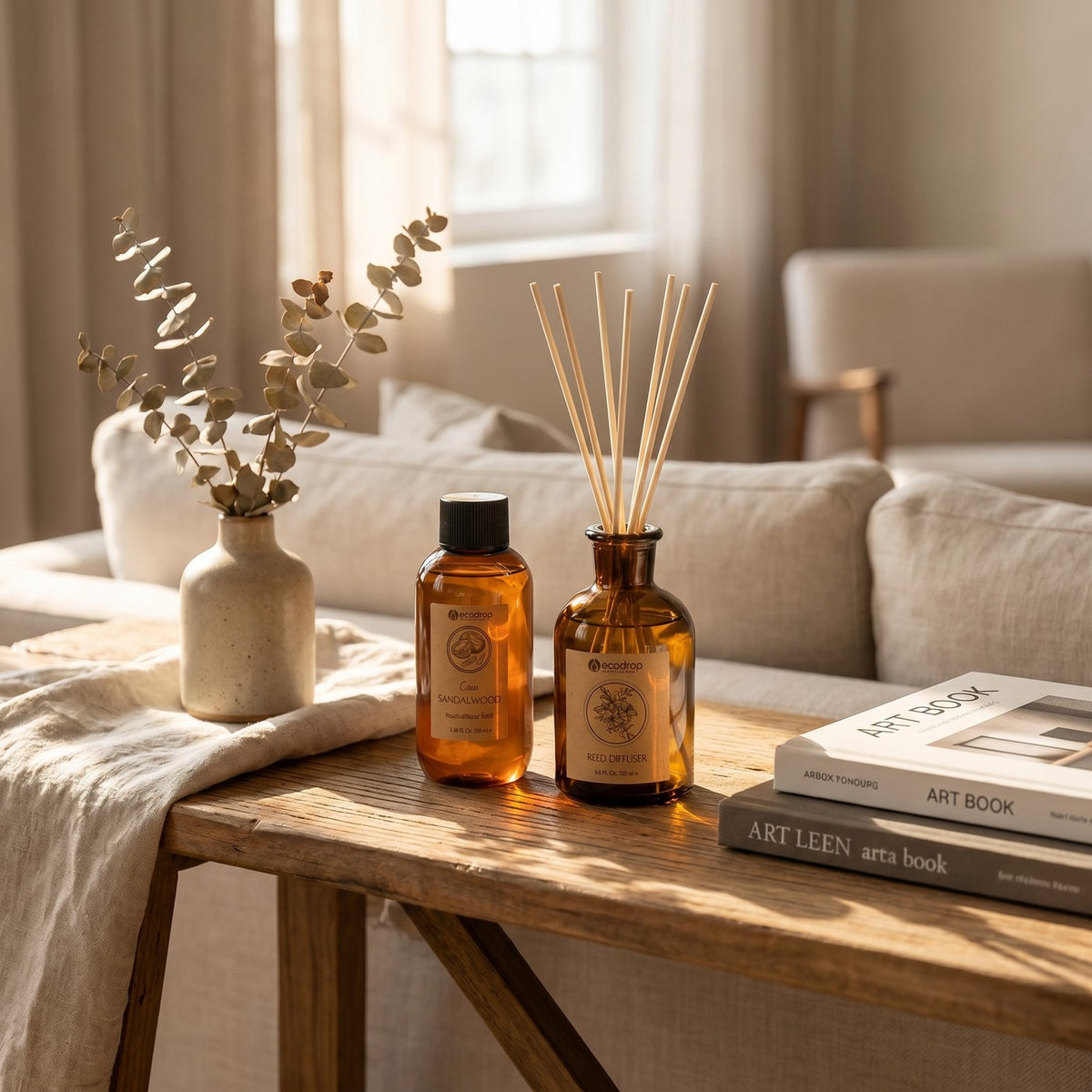 Coco Sandalwood reed diffuser and refill on a wooden bench with eucalyptus and books