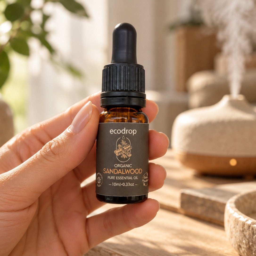 Hand holding a 10ml bottle of Ecodrop Organic Sandalwood essential oil beside a diffuser