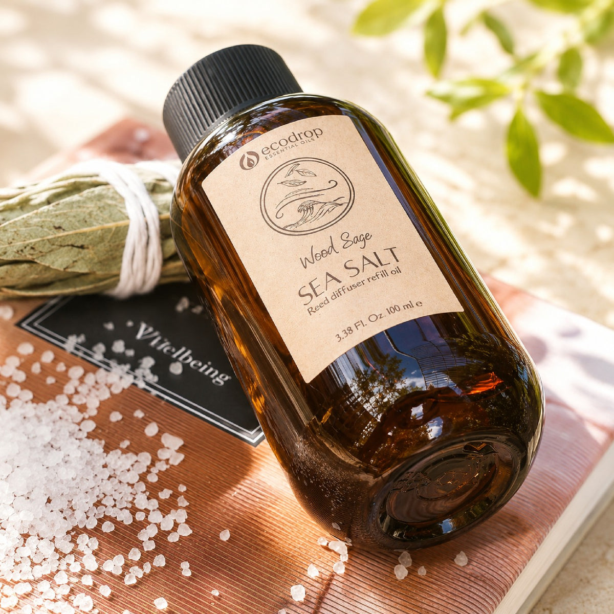 Wood Sage & Sea Salt reed diffuser refill lifestyle - bottle on wellbeing book with sea salt and sage