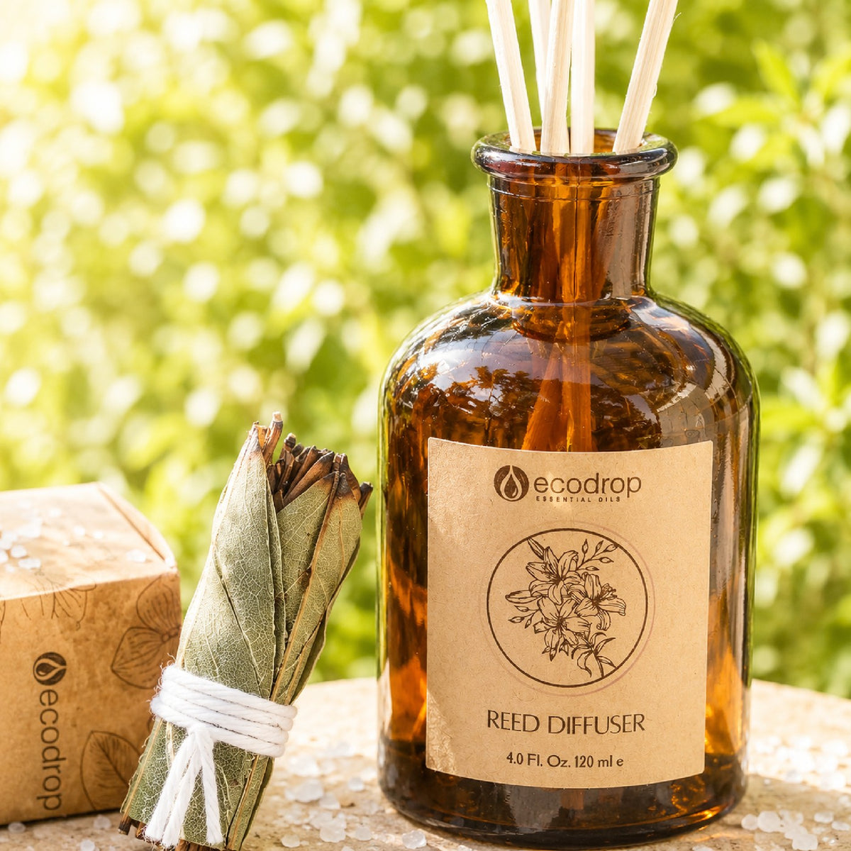 Wood Sage & Sea Salt reed diffuser lifestyle - amber diffuser with reeds outdoors among foliage
